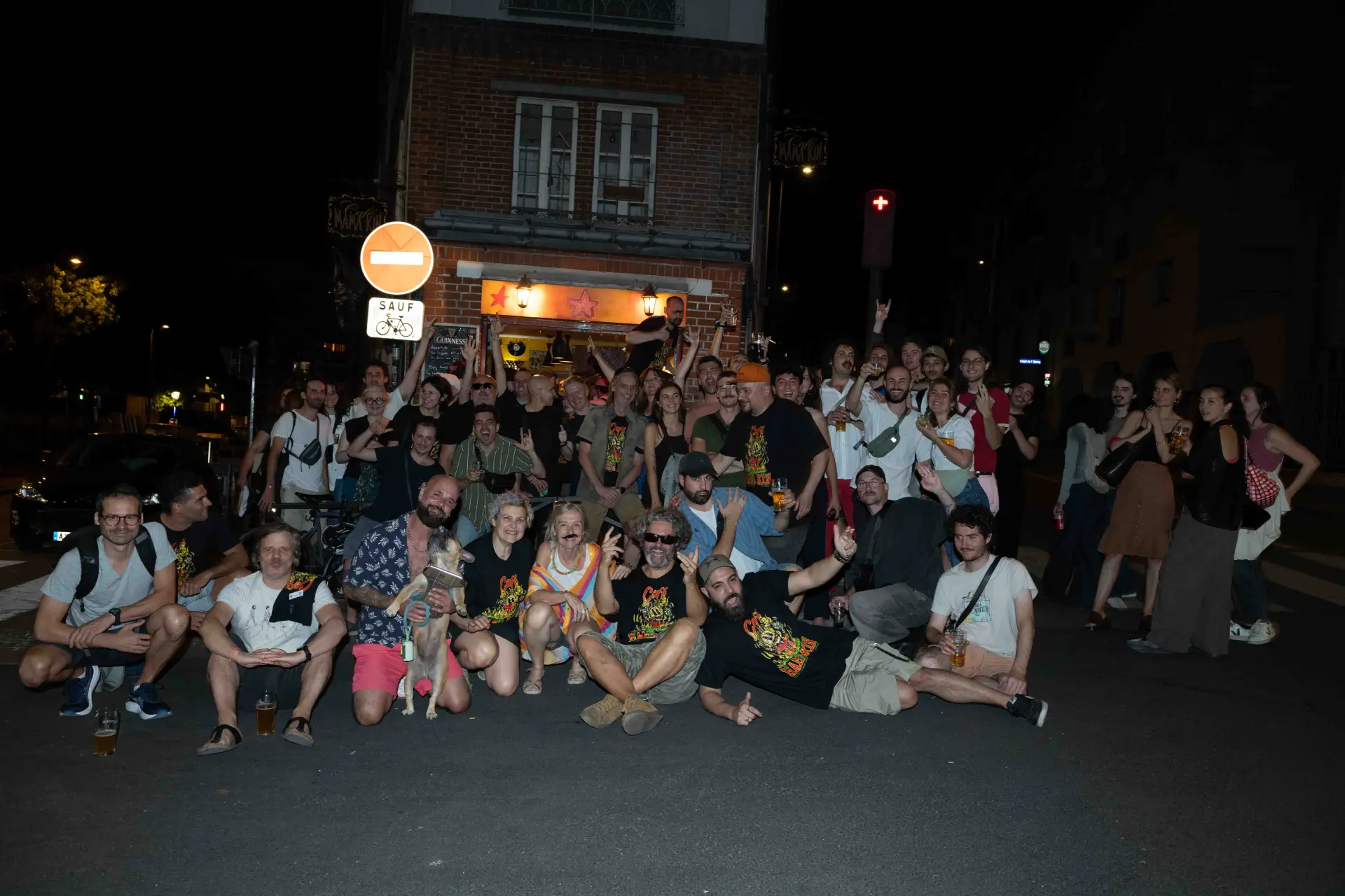 Groupe de personnes posant devant un bar la nuit